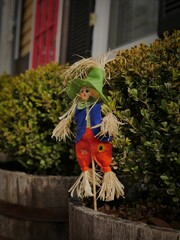 Vertical shot of a small cute scarecrow decoration near a hedge