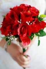 Bride holding her red roses in her hand in a white dress