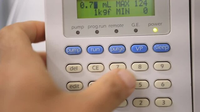 A man programes a pump used for Physicochemical  analysis of organic compounds in water, food and biological samples 
