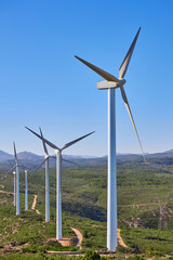 Wind turbines on beautiful sunny summer mountain landscape. Curvy road through mountain wind park. Green ecological power energy generation. Bunol wind farm, Spain.