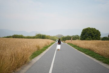 woman walking down a country road with back view of landscape at back