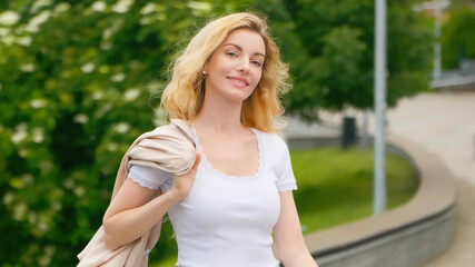 Fototapeta premium Joyful blonde fashionable woman walking having fun smiling in park, relaxing outside, rest, outdoor. Feminine sexy lady portrait, excited relaxed, trend makeup, fashion outfit for beauty, confidence