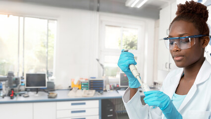 Female African scientist or graduate student in a lab coat working with pipette in laboratory
