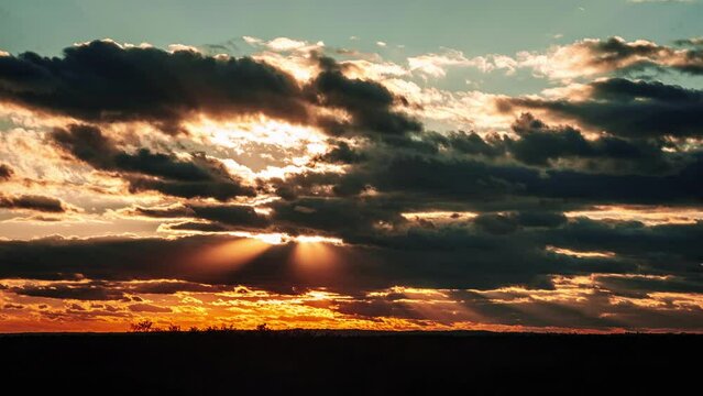 Amazing sunset in dark sky with epic dramatic clouds, Timelapse. 4K. Bright sun setting down above the horizon. Beautiful colorful sunset storm clouds. Vibrant color. Time-lapse. Sundown, Cloudscape