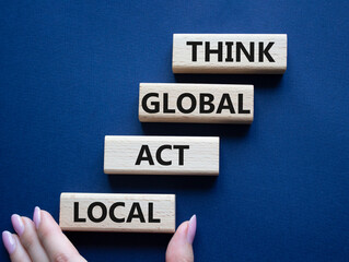 Think global act local symbol. Wooden blocks with words Think global act local . Beautiful deep blue background. Businessman hand. Business and Think global act local concept. Copy space.