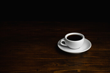 White Cup of black coffee on a wooden table. Copy space