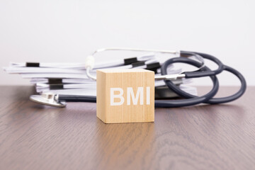 text BMI is written on wooden cube near a stethoscope on a dark background