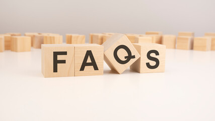 selective focus. word FAQS is written on a wooden cubes structure. blocks on a bright background. can be used for business and financial concept.