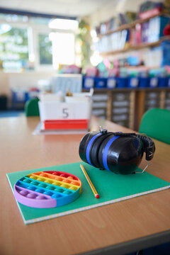 Ear Defenders Or Headphones And Fidget Toy To Help Child With ASD Or Autism On Table In School Classroom