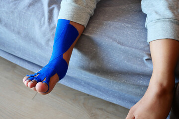 Elastic therapeutic blue tape applied to child leg. Kinesio Taping therapy for injury