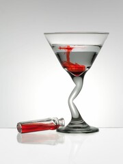 Clear martini glass filled with a vibrant red liquid atop a white table in a well-lit setting