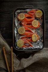 Raw fish trout steak on board on black background with lemon and spices
