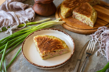 Potato pie with meat on a plate on a wooden background. A piece of potato casserole. Close-up.