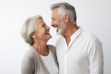 Happy couple in their 60s, smiling, looking at each other, white background