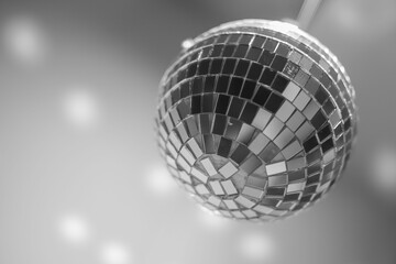 Glittering disco ball hanging upside down from the ceiling, illuminating the room in grayscale