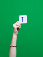Lettre en carton et bois tenue par une main d'enfant sur fond vert détourage facile pour création...