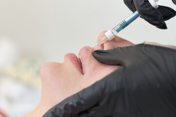 Client receiving a lip filler treatment. Beauty aspirations meet modern medical interventions.