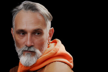 Grey-haired, mid-aged senior mature man isolated on dramatic black background. Confident presence illustrates beauty and character comes with aging gracefully and richness of individual's experiences.