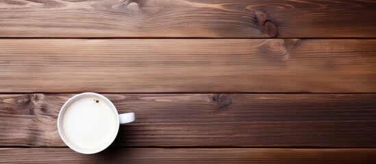 A wooden desk in an office holds a coffee cup along with a notebook and paper
