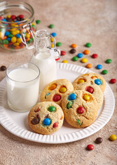American cookies with colorful chocolate candy drops served with glass of milk. Delicious homemade dessert for children.