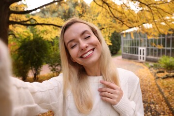 Portrait of happy woman taking selfie in autumn park