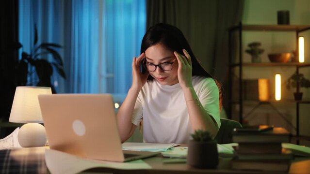 Portrait of exhausted young asian woman with head on her hands feeling upset while take a break at home Tired female with failed ideas creative block or lack of inspiration indoors