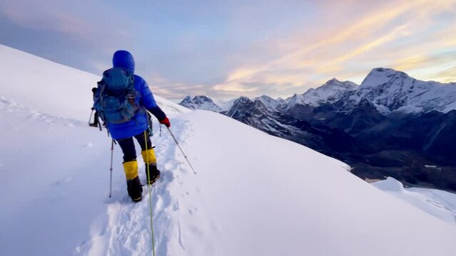 Last steps before Mera peak summit 6476m rope team dressed mountaineering clothes, boots with crampons ascending steep snowy slope. Himalaya mountains 4K handheld camera footage.