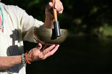 Mature adult man holding a Tibetan singing bowl and the accompanying stick