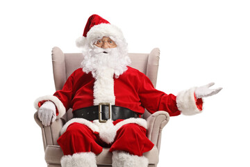 Santa claus seated in an armchair and showing something with hand