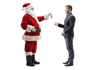 Full length profile shot of santa claus giving a car key to a young man