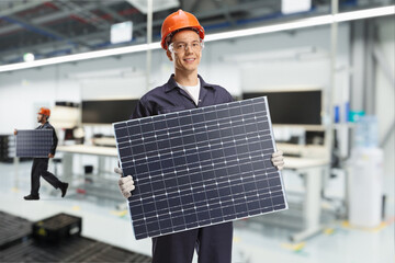 Workers inside a factory carrying solar panels