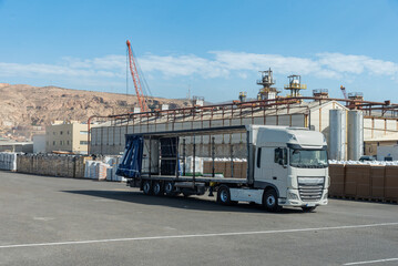 Truck with the side canvases open and empty waiting to be loaded with pallets with peat in a port.