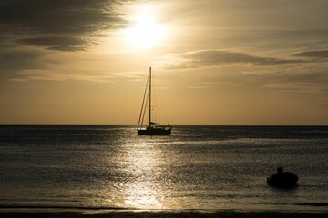 Fototapeta premium Small vessel sailing across the ocean at sunset