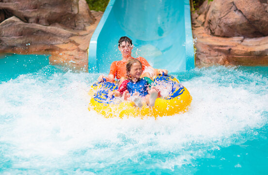 Kids on water slide. Family in aqua theme park.