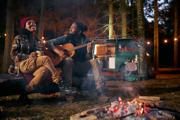 Romantic black couple enjoys in acoustic music by campfire at night.