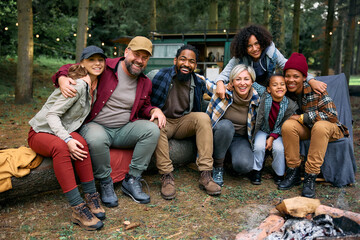 Two happy families camping together in woods and looking at camera.