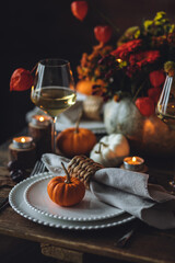 Cozy festive holiday table decor for home family Thanksgiving dinner. Traditional event, elegant natural decoration. Wooden rustic table, countryside style. Burning candles, floral centrepiece pumpkin