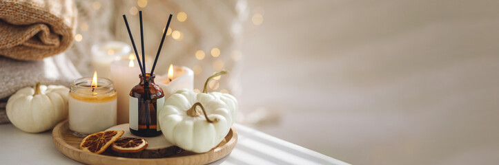 Still life details in the living room. Autumn composition with aroma diffuser with pumpkin pie scent, knitted sweaters, candles. Concept of slow life, relaxation, detention. Apartment decor banner - obrazy, fototapety, plakaty