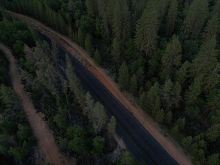 Aerial view of a train track passing through lush green forest at dusk