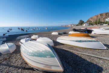 Wide angle photo of upside down wooden fishing boats on a beach in Andalusia (Spain) on a sunny autumn morning - obrazy, fototapety, plakaty