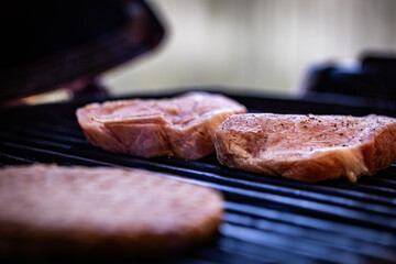 Pair of frozen pork chops placed on the grate of a barbecue for grilling