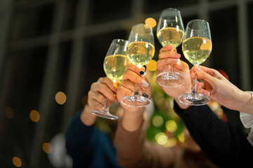 close up glasses of clinking glasses of champagne with lighting. Dinner party with drinking of champagne. hands holding clear glass with alcohol in yellow shine reflect.