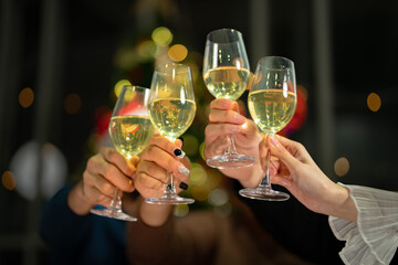 close up glasses of clinking glasses of champagne with lighting. Dinner party with drinking of champagne. hands holding clear glass with alcohol in yellow shine reflect.