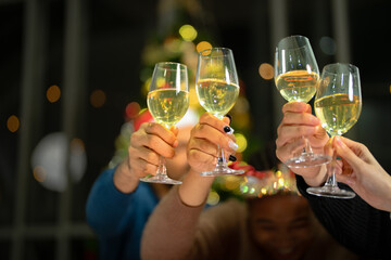 close up glasses of clinking glasses of champagne with lighting. Dinner party with drinking of champagne. hands holding clear glass with alcohol in yellow shine reflect.