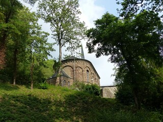 Fototapeta na wymiar an old stone church sitting among green trees in the mountains