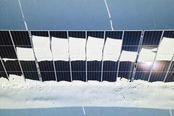 Aerial view of electrical power plant with solar panels covered with snow melting down in winter end for producing clean energy. Concept of low effectivity of renewable electricity in northern region