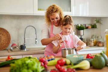 Mother and daughter preparing tasty food at home