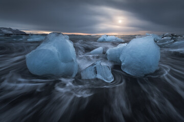 Broken ice on black beach in sea water in Iceland