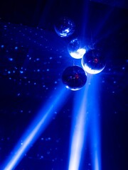 Vertical shot of disco balls and blue neon lights at the club