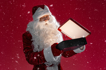 Santa Claus holding and opening gift box isolated on red background. Holiday, Marry Christmas, magic concept